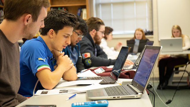 Students study behind laptops in class