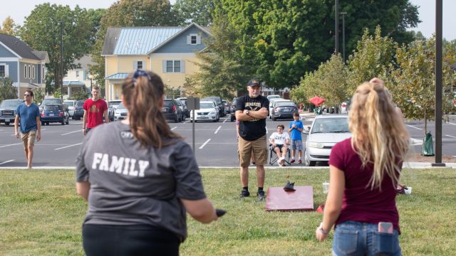 Students and families play cornhole on campus
