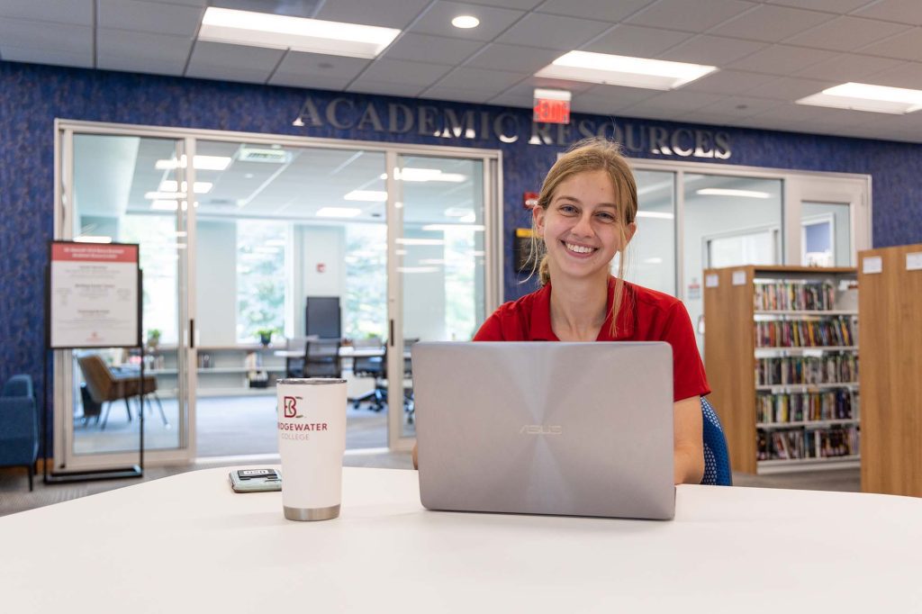 Student sitting outside the Academic Resources office with laptop