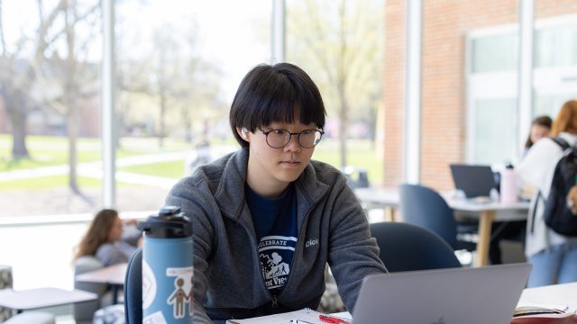 Student with glasses working on laptop