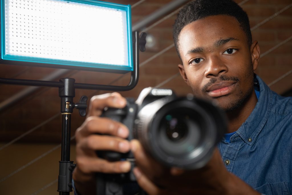 Student looking directly at camera with camera in hand 