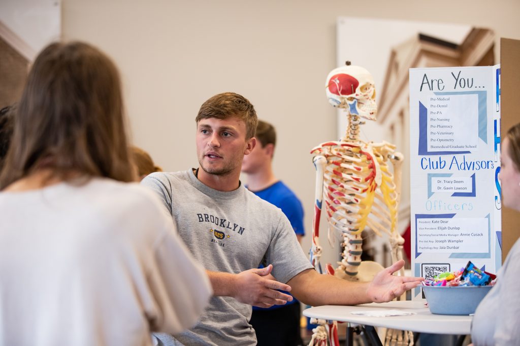 Student pointing to information board about a club