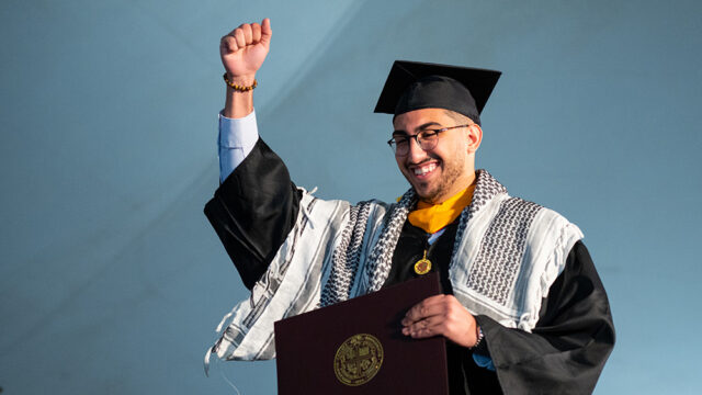 Student raising fist in the air out of excitement he just graduated