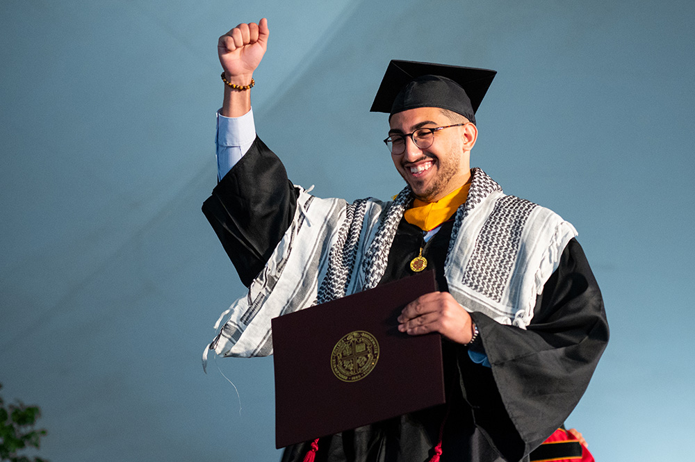 Student raising fist in the air out of excitement he just graduated