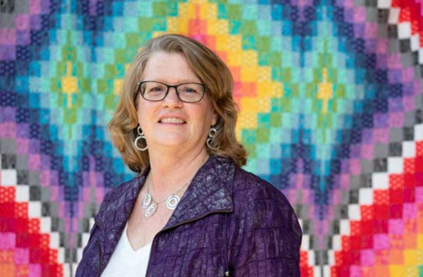 Ann Rainard in front of a quilt