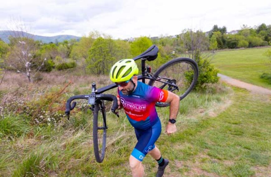 Dr. Christian Sheridan carries his bike over one shoulder