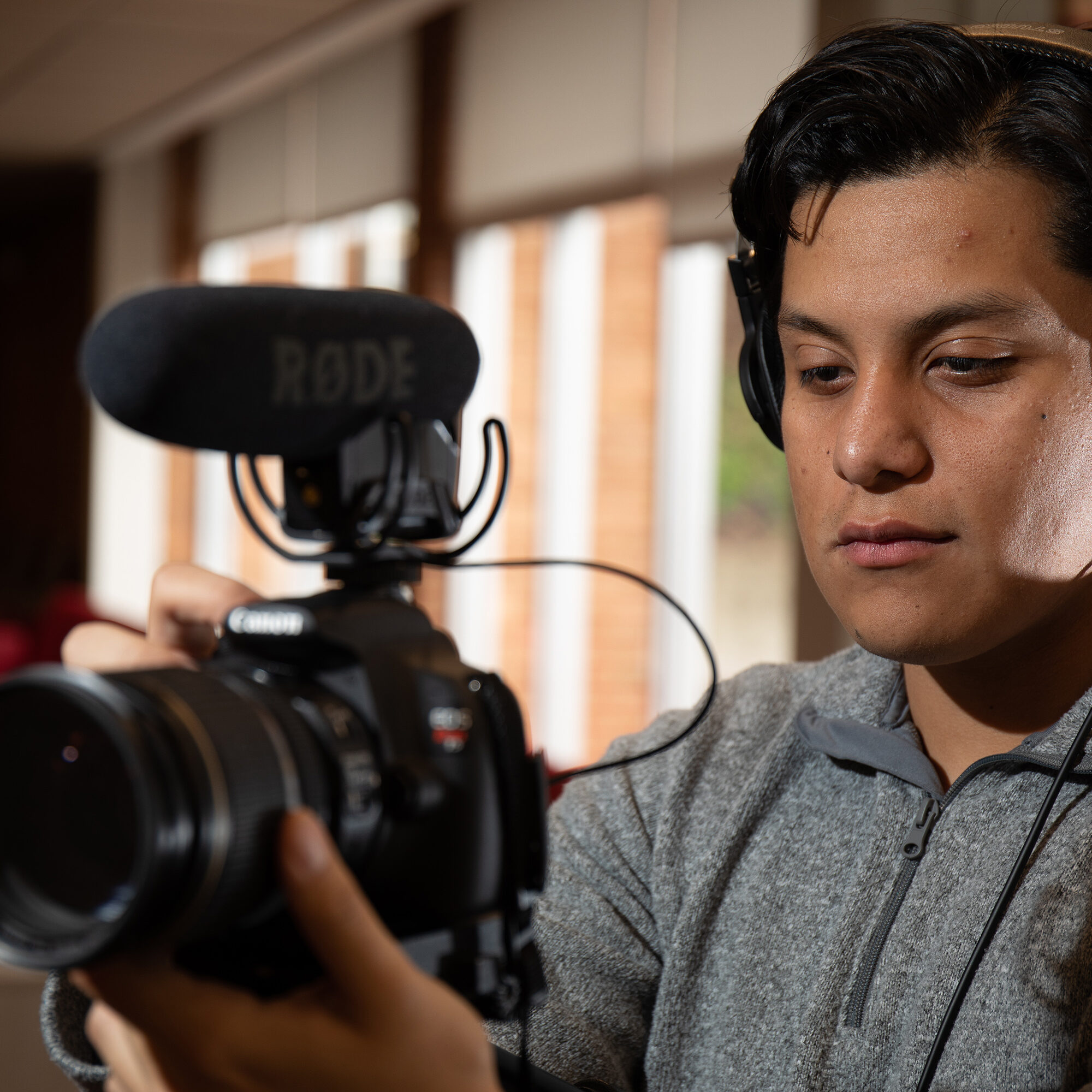Student with headphones holding camera with microphone